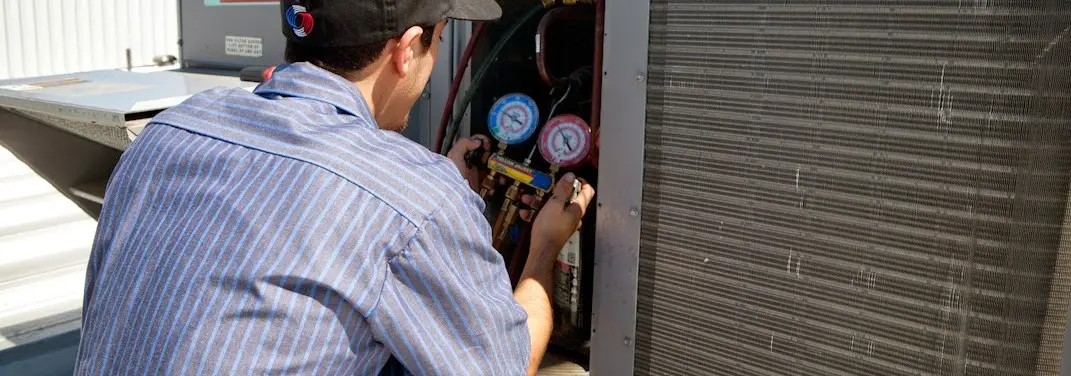 HVAC technician servicing a condenser unit in Cumberland